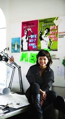 Creative smiling female student sitting on table 